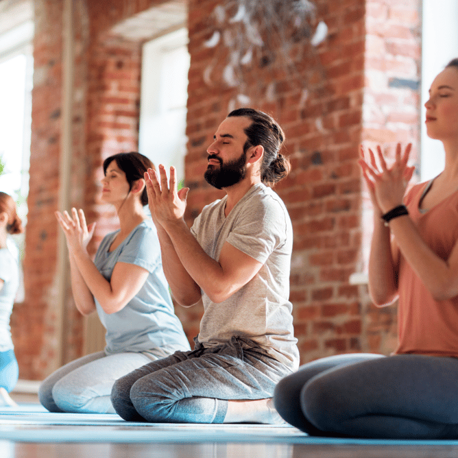 middle-aged man and woman practicing mindfulness in a group fitness class setting at a gym